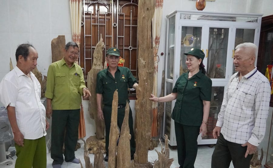 Ông Phạm Thanh Đàn, bà Lê Thị Thạo (đội mũ, đứng giữa) giới thiệu các sản phẩm trầm cảnh của gia đình với các cựu thanh niên xung phong trong xã - Ảnh: L.M