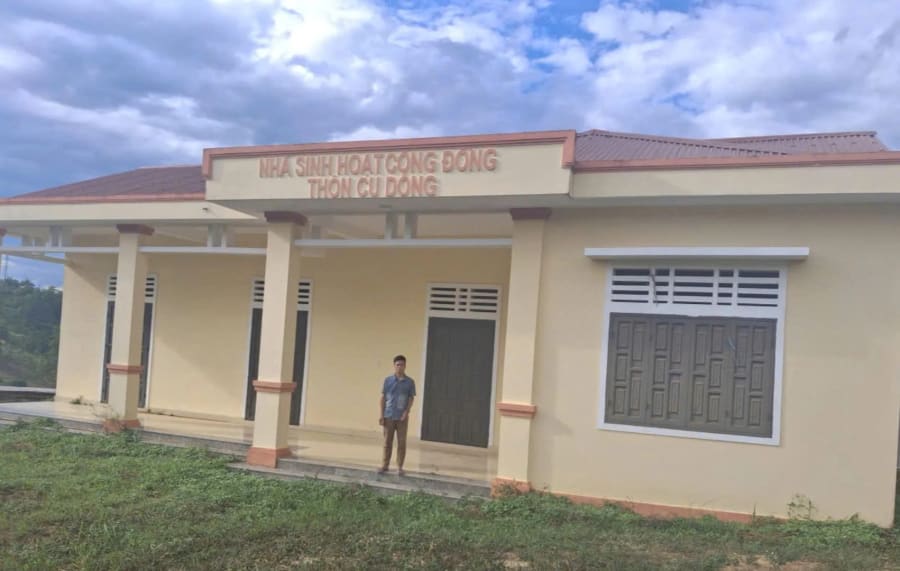 Anh Hồ Văn A Rực bên nhà sinh hoạt cộng đồng thôn Cu Dông cũ khang trang được xây dựng trên mảnh đất của gia đình anh hiến tặng - Ảnh: K.S