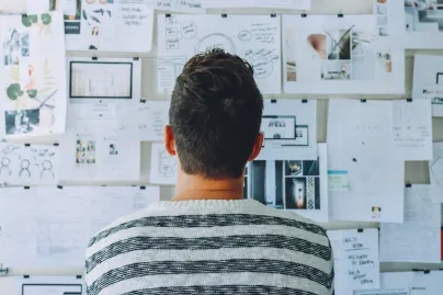 man looking at wall of printed pages