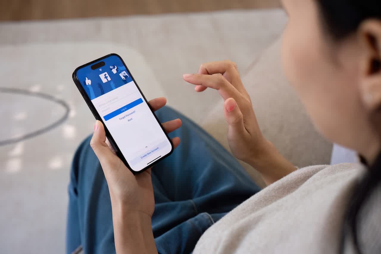 Person seated using their phone, which shows Facebook app