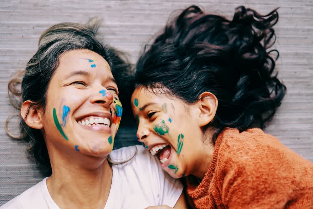 A woman and child painting and laughing.
