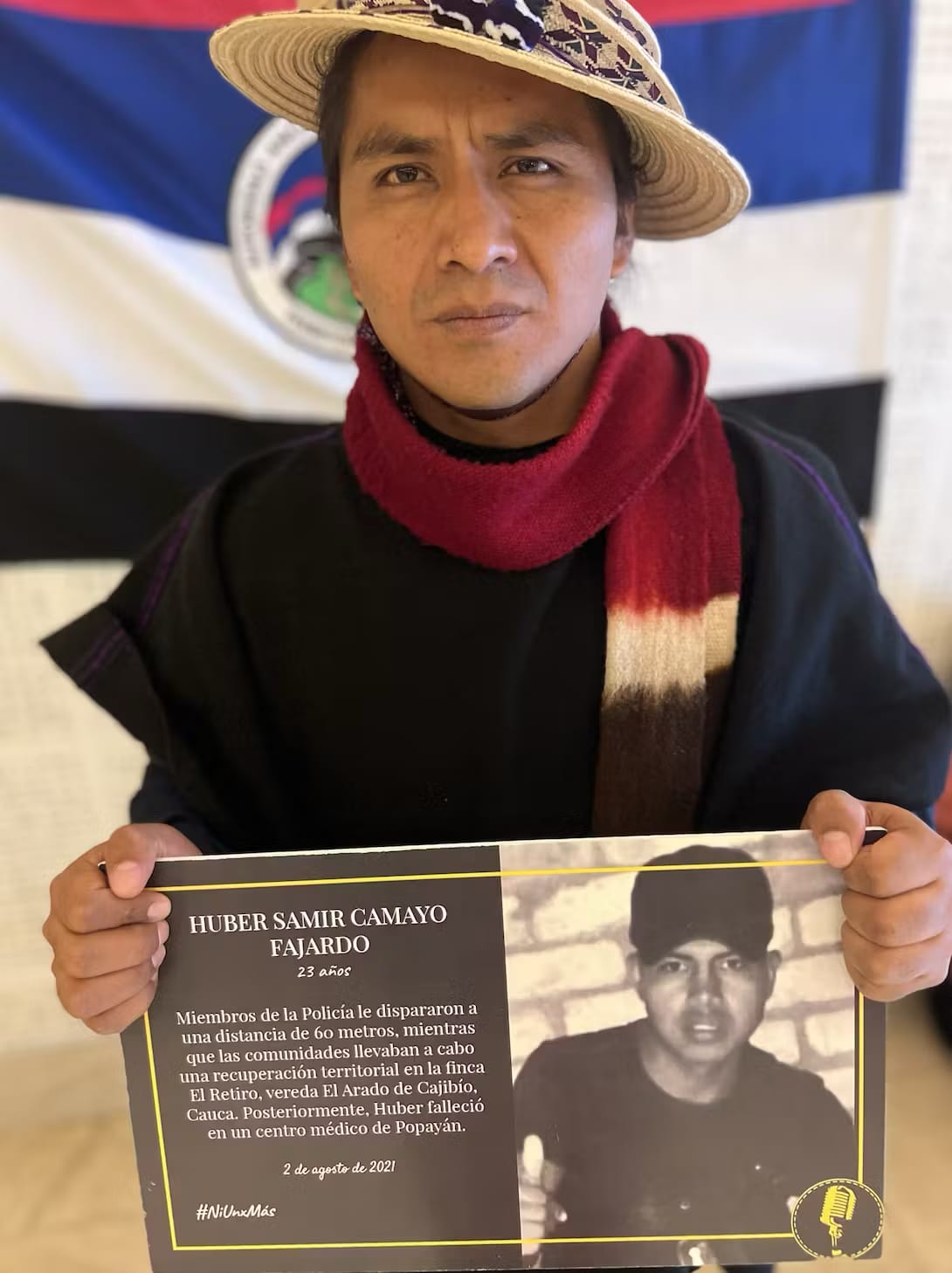 Indigenous leader Pedro Josse Velasco Tumiña holding a poster denouncing the killing of Huber Samir Camayo