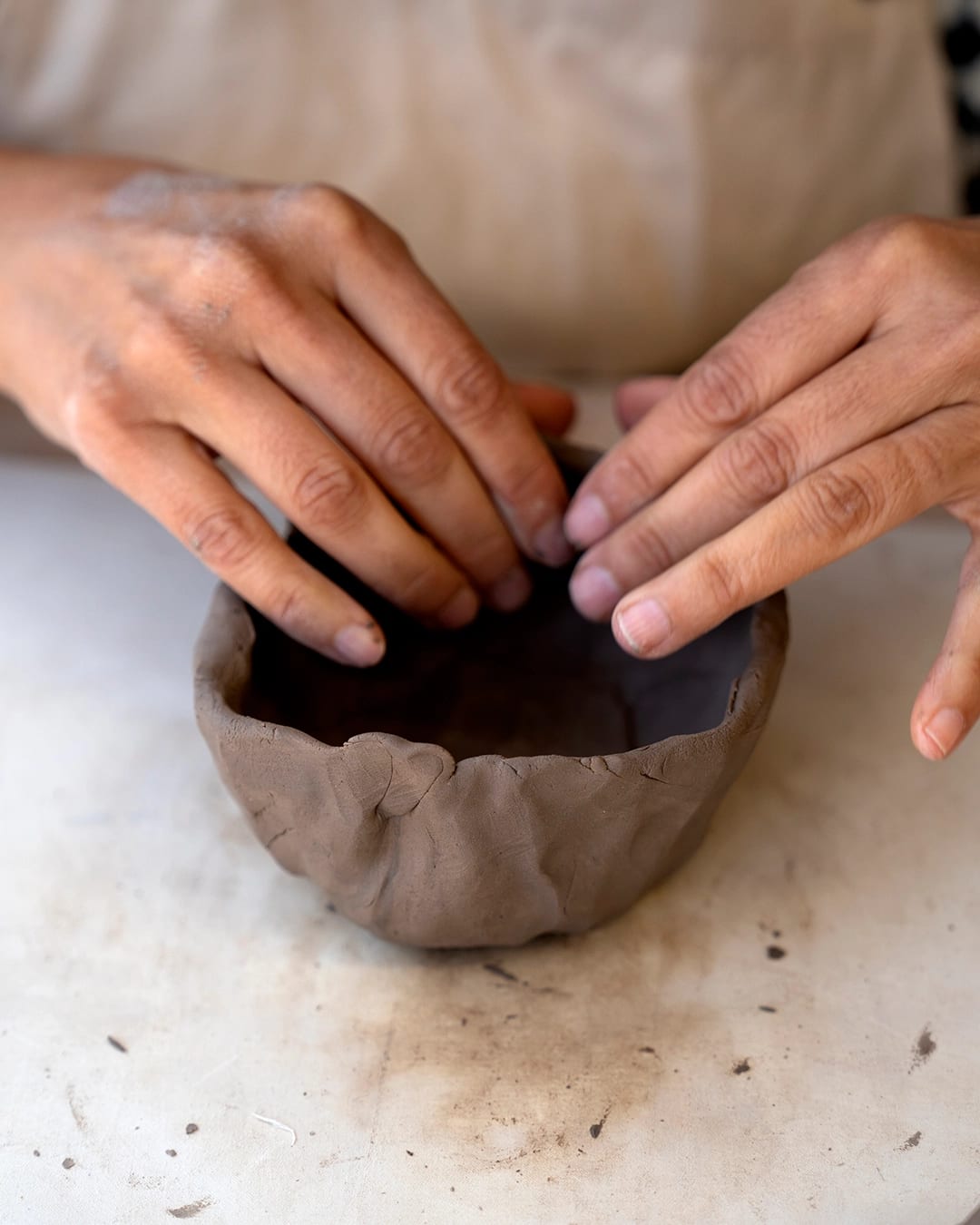 Manos trabajando sobre pieza de cerámica cruda