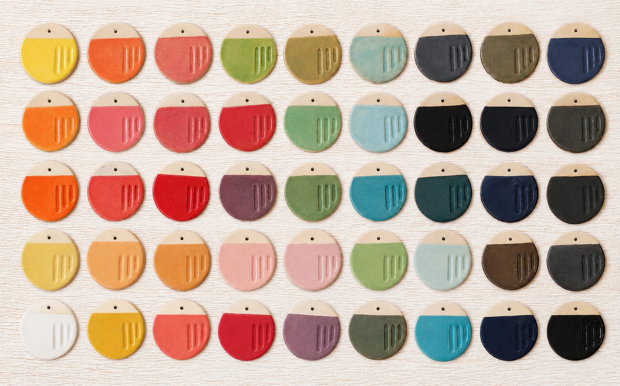 Vista cenital de muestras de cerámicas de colores ordenadas sobre una mesa blanca