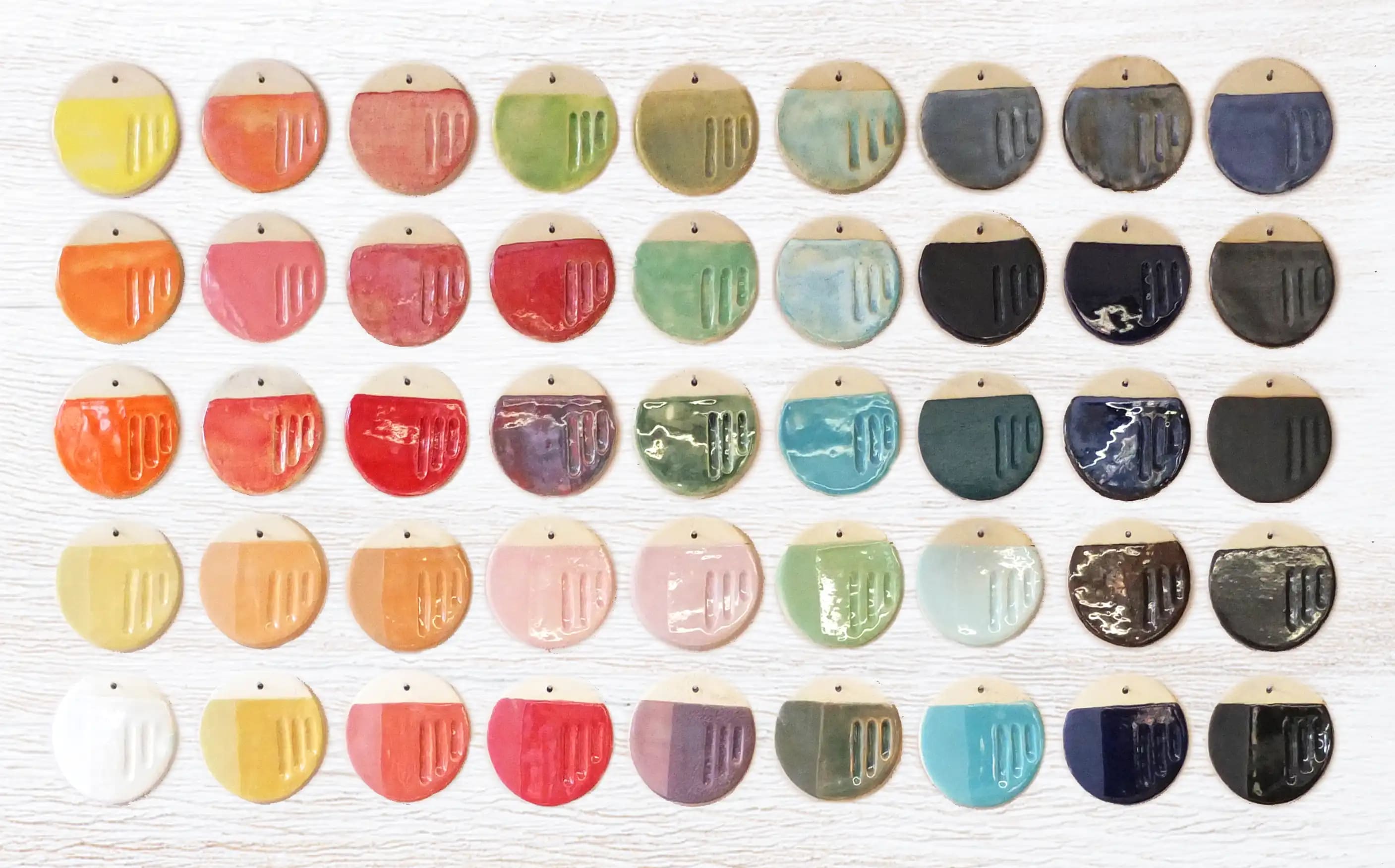 Vista cenital de muestras de cerámicas de colores ordenadas sobre una mesa blanca