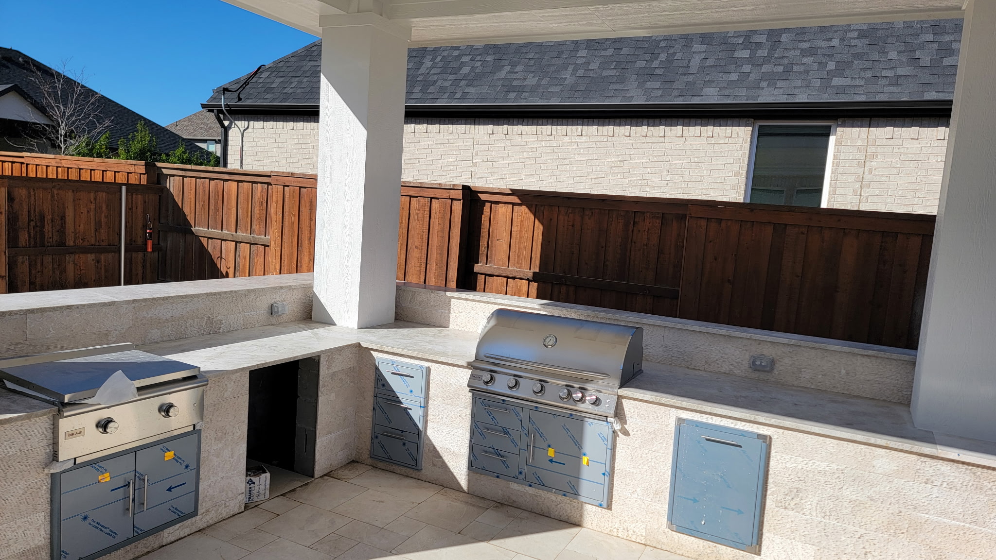 Custom outdoor kitchen with built-in grill and prep area, featuring stone countertops and cabinetry, designed for seamless outdoor living and entertaining.