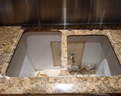 Granite countertop with cutout for double sink installation, showing exposed plumbing and unfinished edges, highlighting a service call for repair and restoration by Dallas Granite Installers.