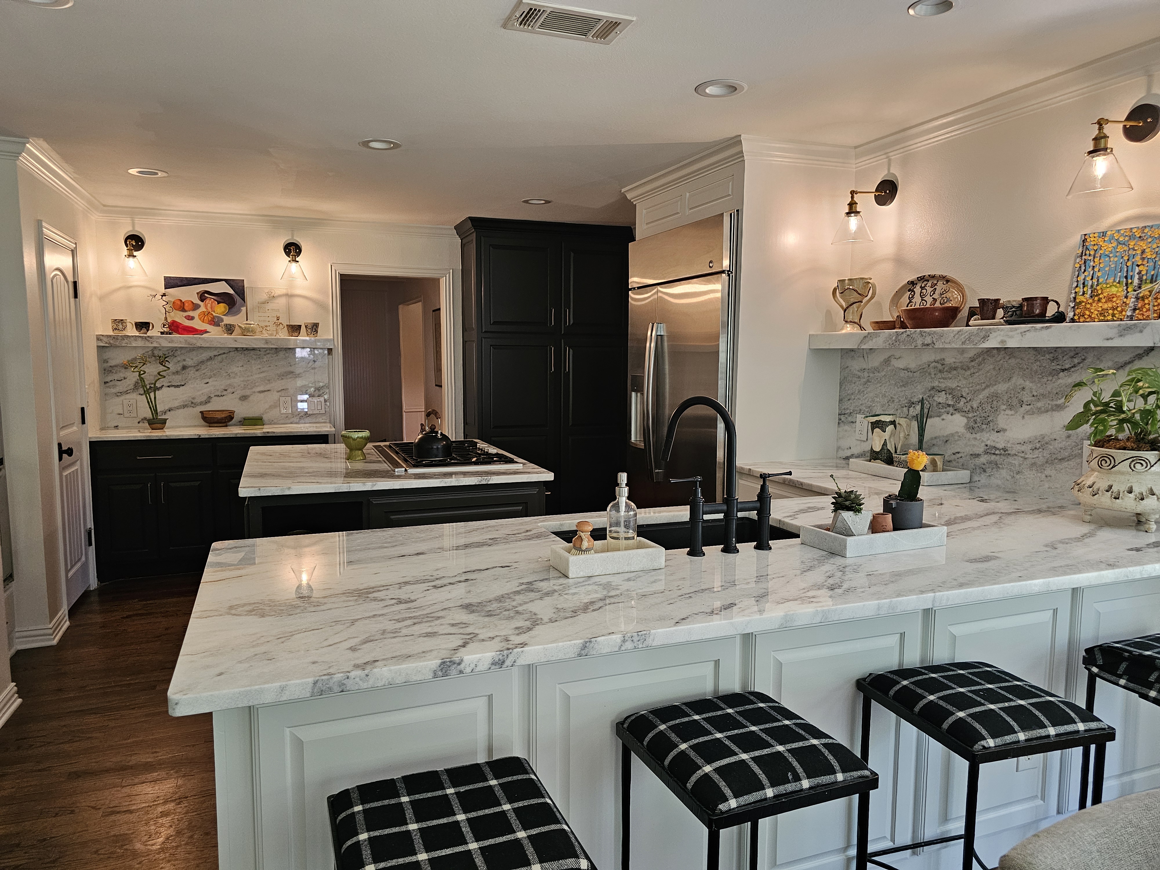 Modern kitchen showcasing elegant granite countertops, black cabinetry, and stylish bar stools, highlighting durability and aesthetic appeal for high-impact spaces.
