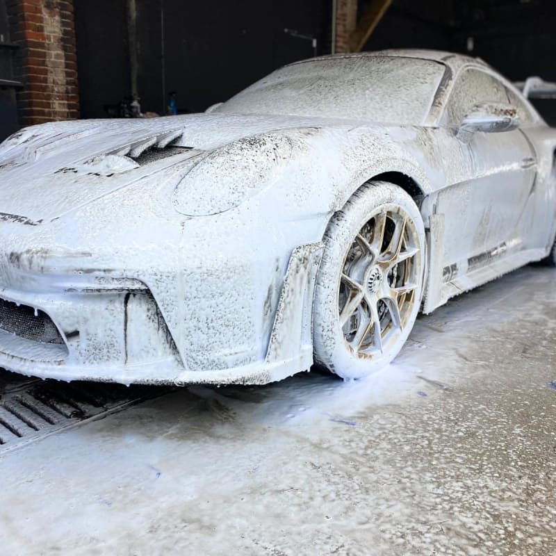 Porsche 911 GT3 RS argentée sous snow foam — vue 3/4 avant détail jante et flanc