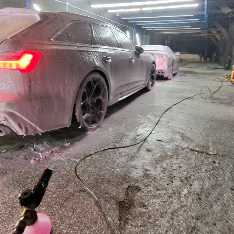 Audi RS6 Avant grise — vue 3/4 arrière sous prélavage snow foam rose