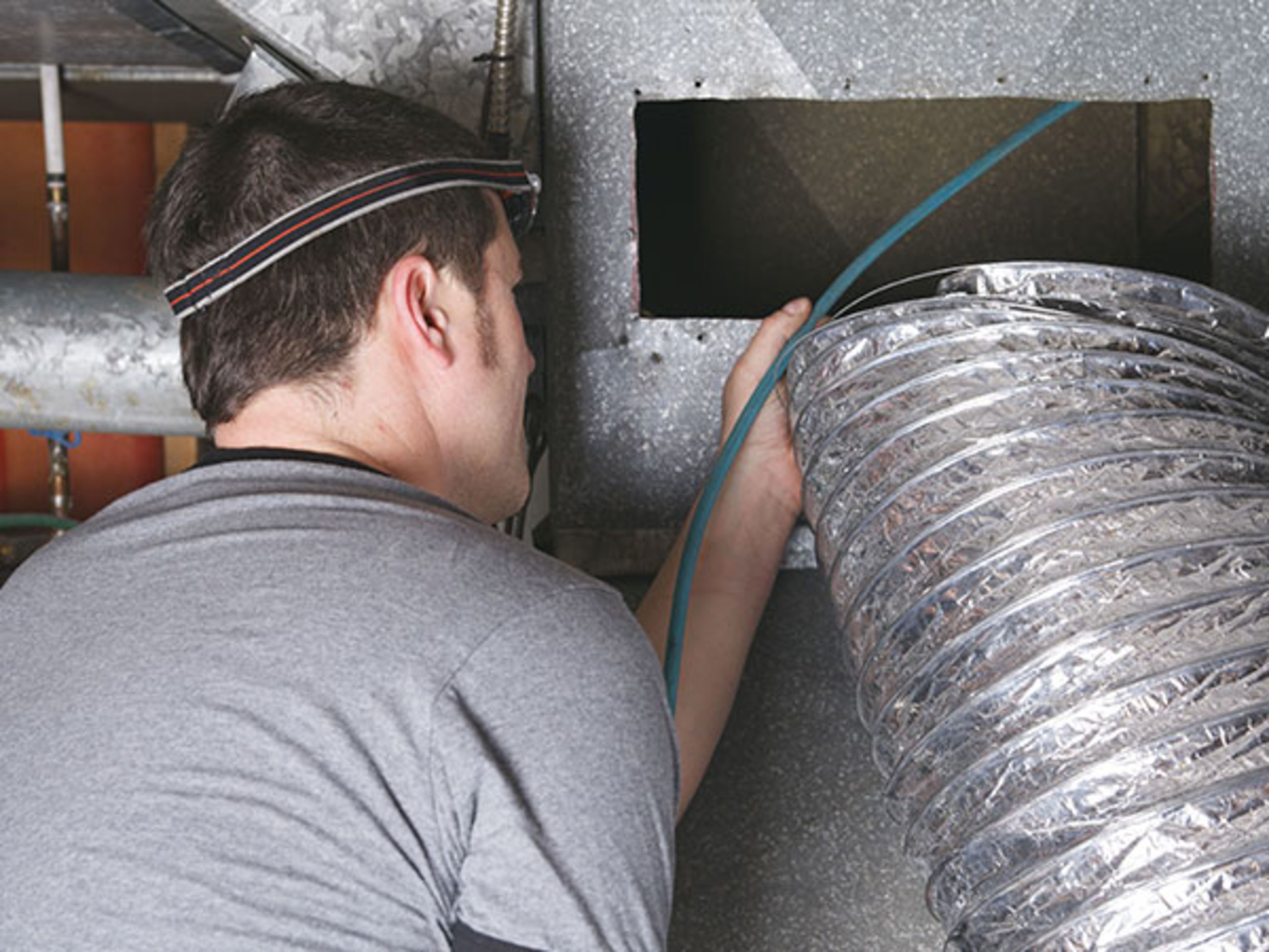 Air duct technician inspecting air duct