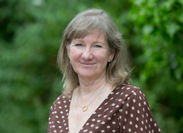 A woman, Lesley Macdonald, standing in front of a shrub