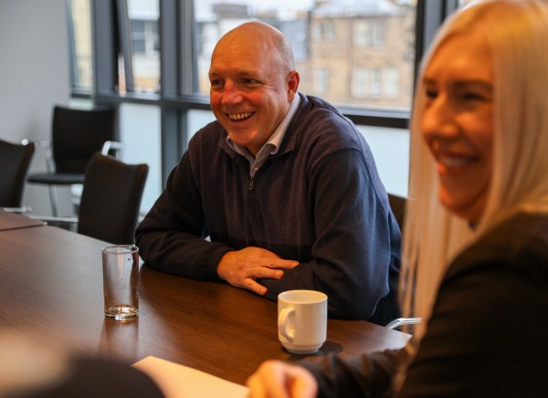 Two people sitting at a table, smiling and engaged in conversation.