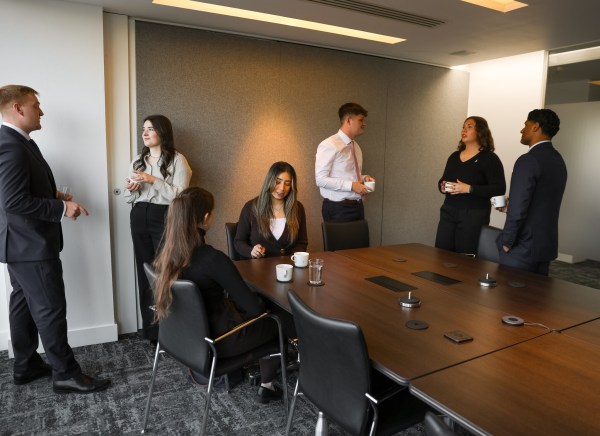 A group of professionals chat and network in a modern conference room.