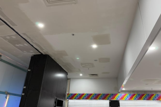 Commercial ceiling with exposed plasterboard patches and unfinished surfaces prior to painting. Commercial painting preparation by Blue Collar Painting, Gold Coast.