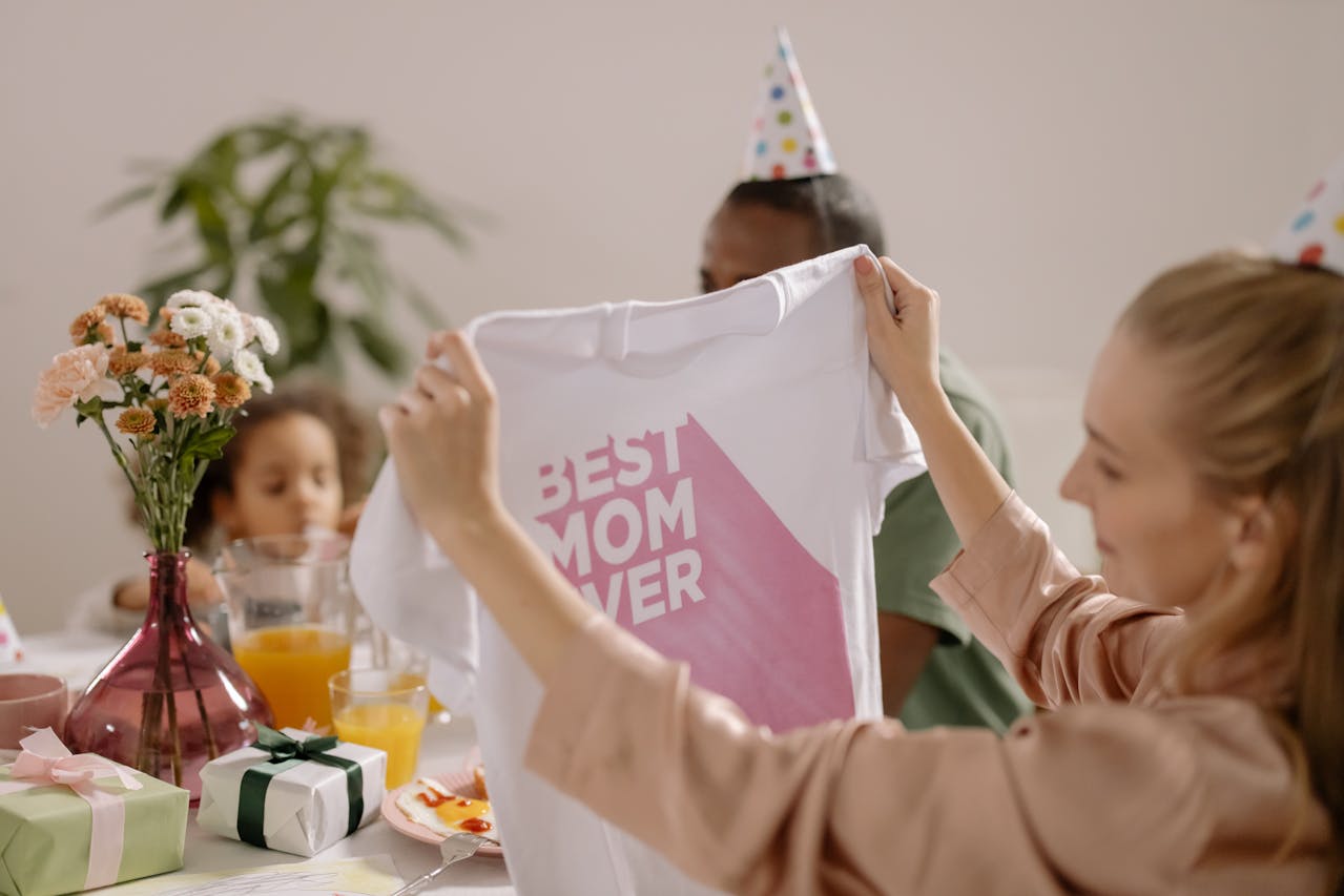 A joyful indoor Mother's Day celebration featuring a family with a 'Best Mom Ever' shirt