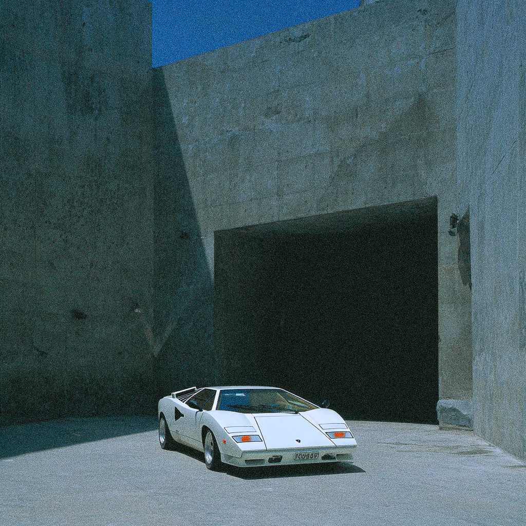A white sports car parked in front of a dark tunnel entrance.