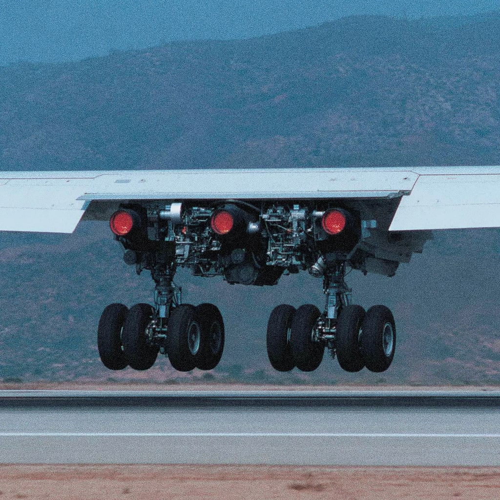 A close-up view of an airplane's landing gear with red lights on the wing.
