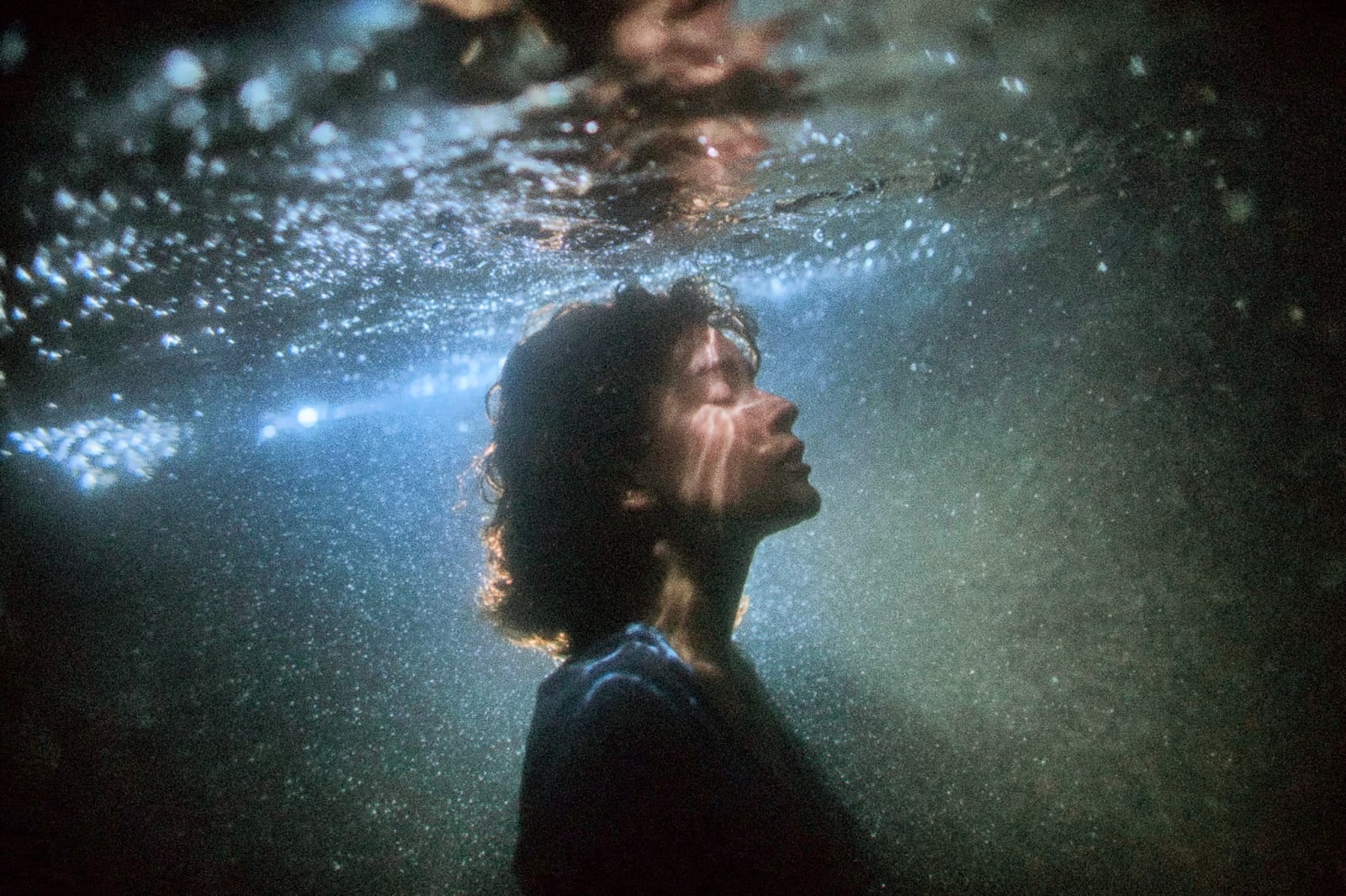 A person underwater with bubbles and light beams.
