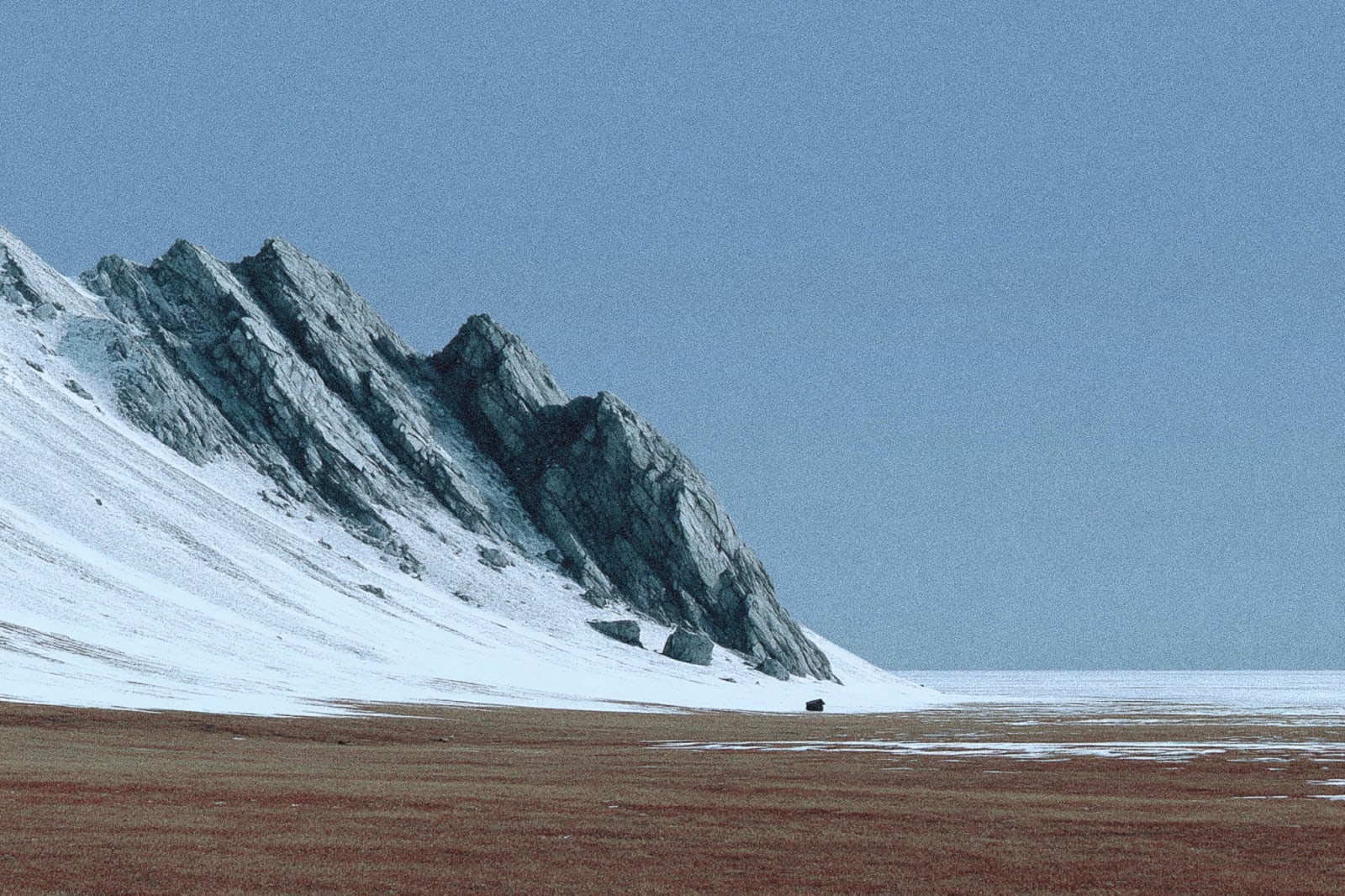 A snowy mountain peak with a clear blue sky above.