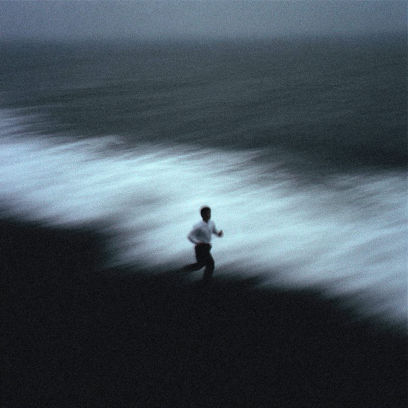 A person running on a dark, misty landscape.