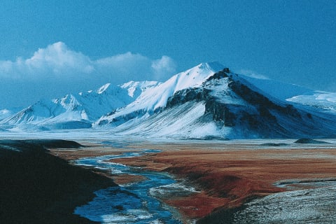 Snow-covered mountains and a winding river in a vast landscape.