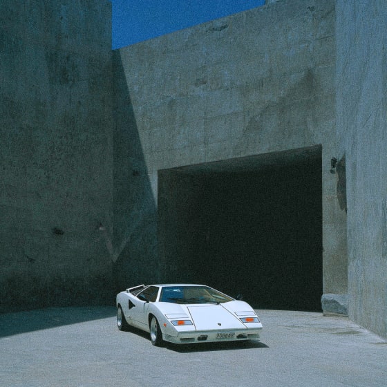 A white sports car parked in front of a dark tunnel entrance.