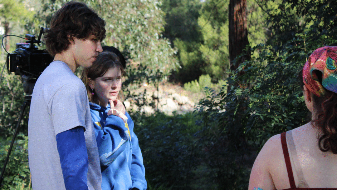Three filmmakers speaking in a park