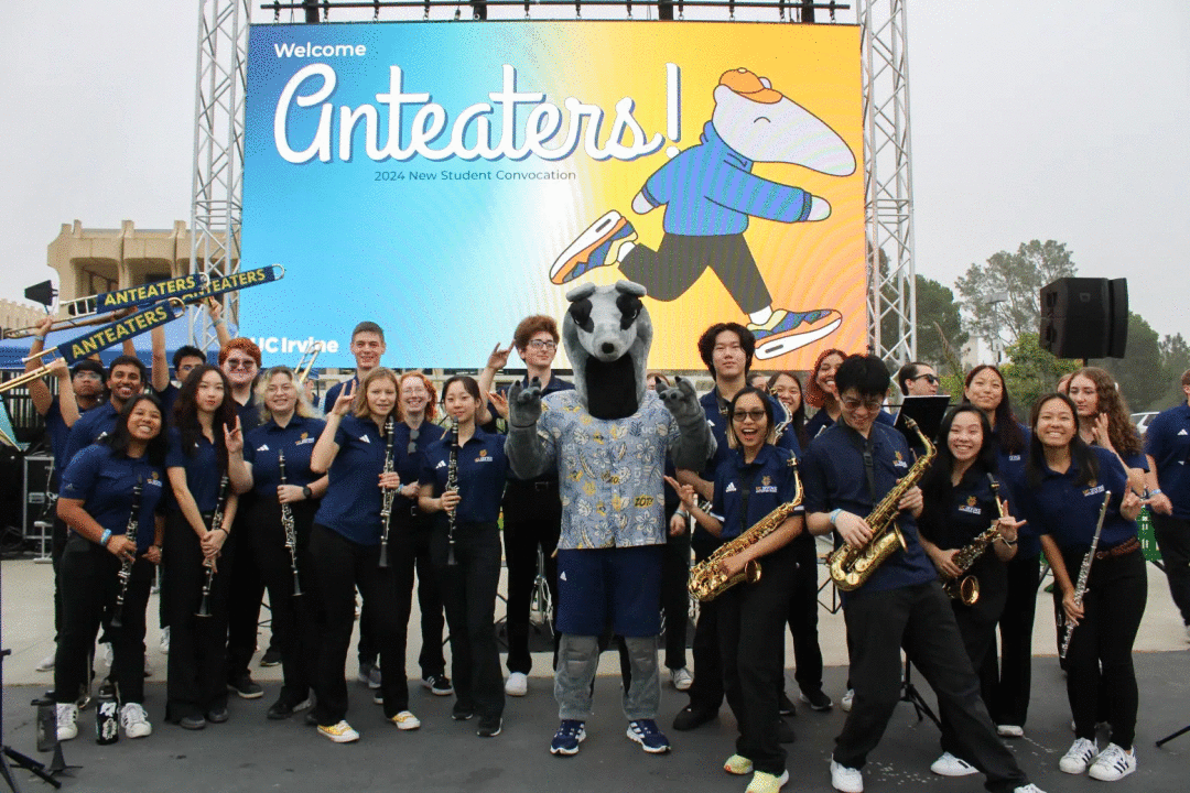 A group picture of a pep band in front of a jumbo screen