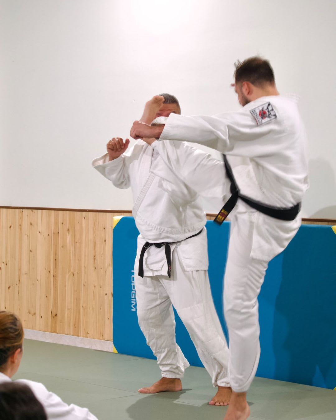 Dois faixas pretas a demonstrar uma defesa com joelhada numa aula de Krav Maga