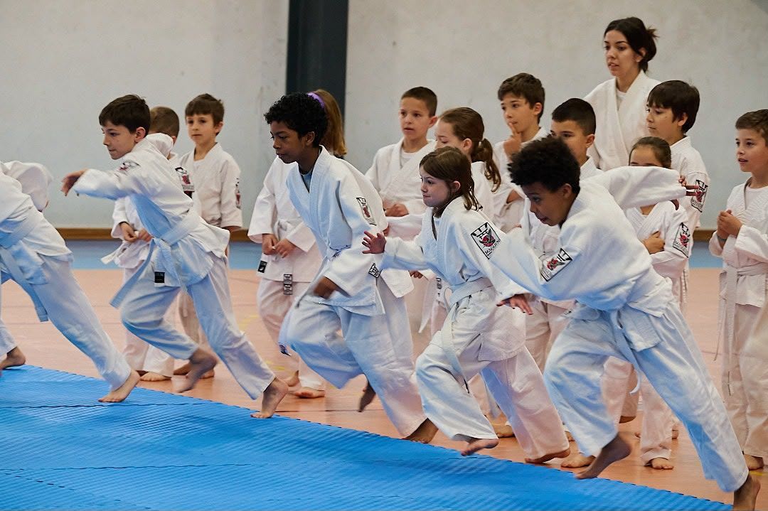 Turma de crianças de quimono a fazer um exercício de deslocamento numa aula de Krav Maga