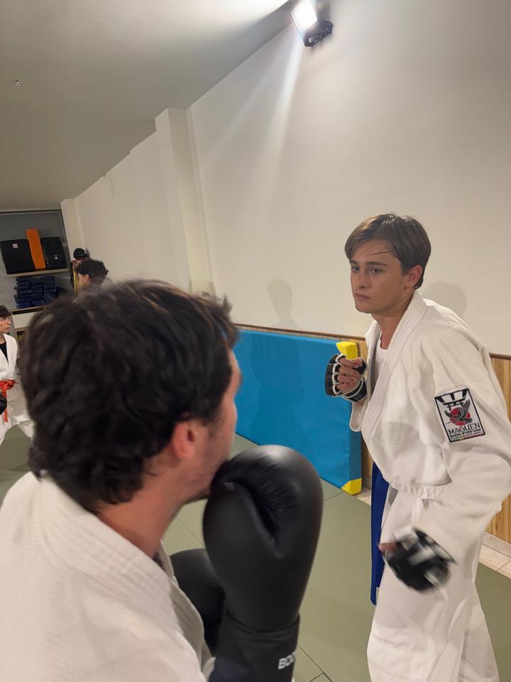 Aluna de quimono com luvas pronta para um exercício de impacto com o colega