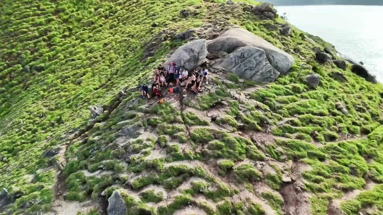 Съёмка с дрона: хайкеры на зелёном склоне над морем на Пхукете