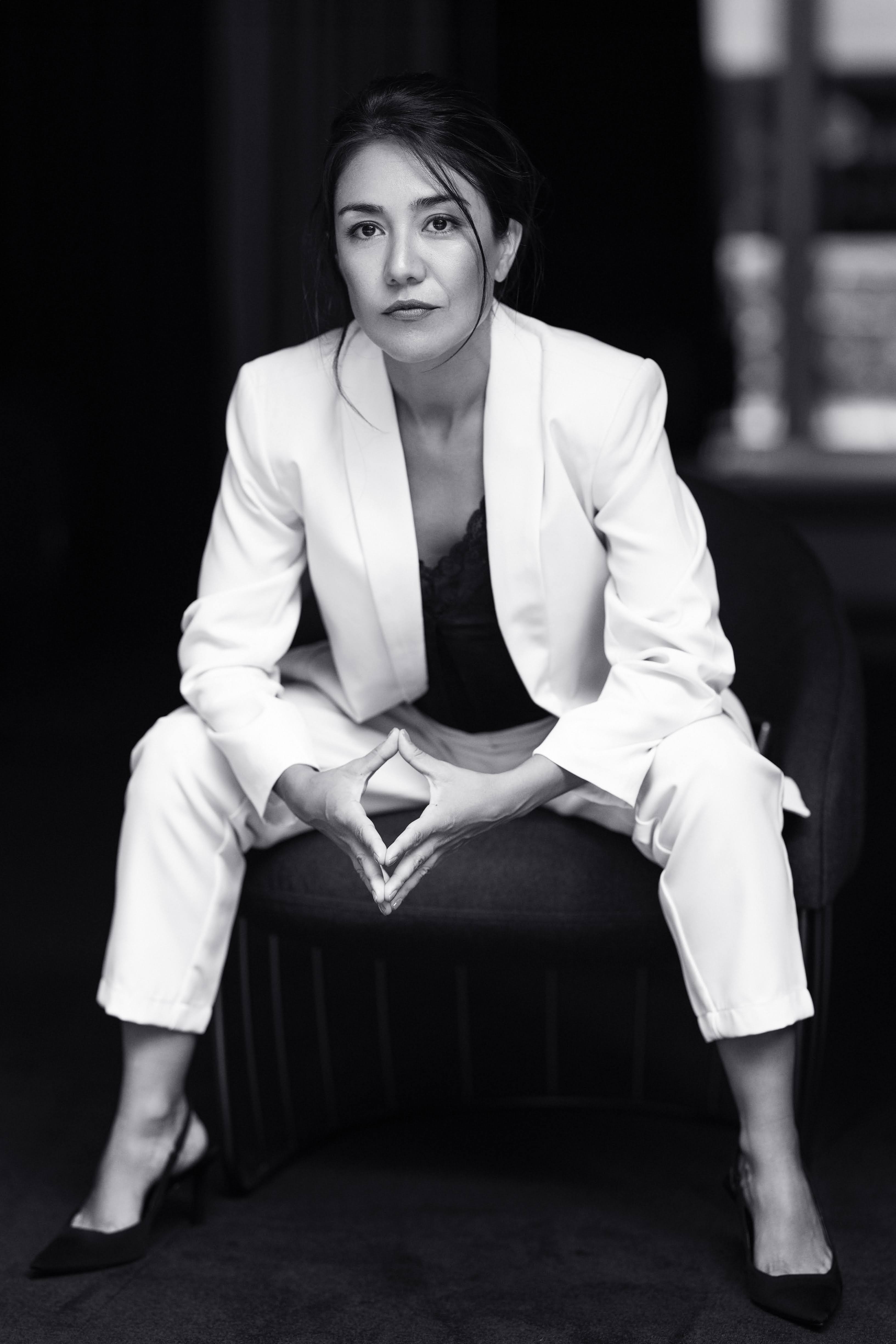 Natalia Cacciari Garavito, seated in a white suit, in a black-and-white portrait