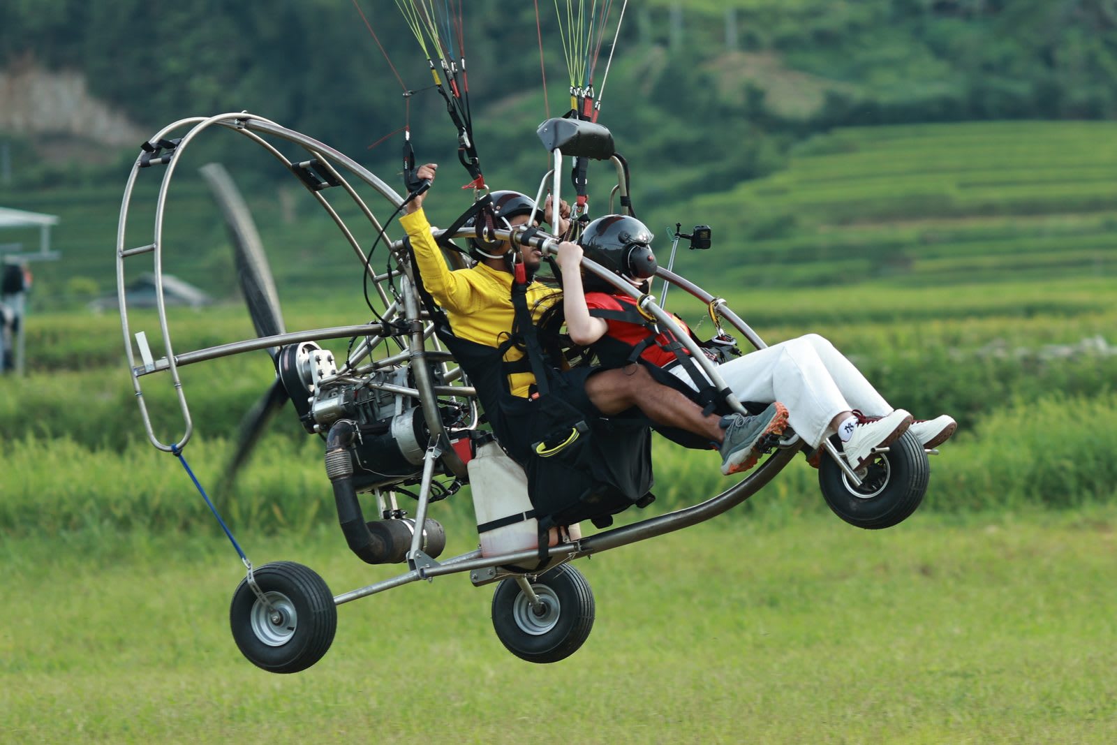Xe trike PPG hai người ở Khau Phạ, nhìn ngang: riser móc vào điểm treo trên khung, tay phi công giơ lên tới tầm tay phanh. Ảnh minh hoạ; xe trike nằm ngoài phạm vi bài này. Ảnh: Mebayluon