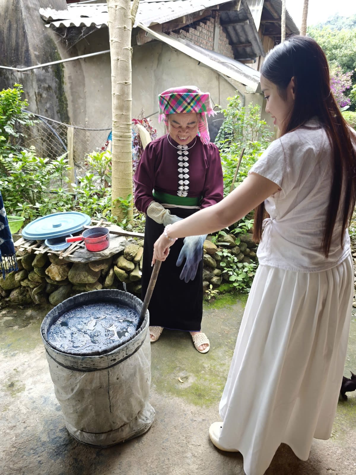 An elderly Thái woman stirring a vat of indigo dye in Ít Thái village