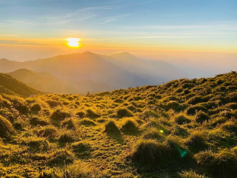 Sunrise over the grassy hills near the summit of Lùng Cúng