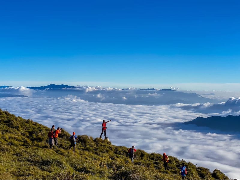 A trekker on the summit slopes of Lùng Cúng above a sea of clouds