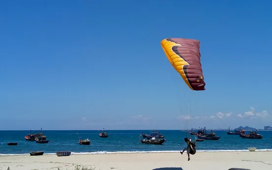 A paraglider pilot landing near the beach