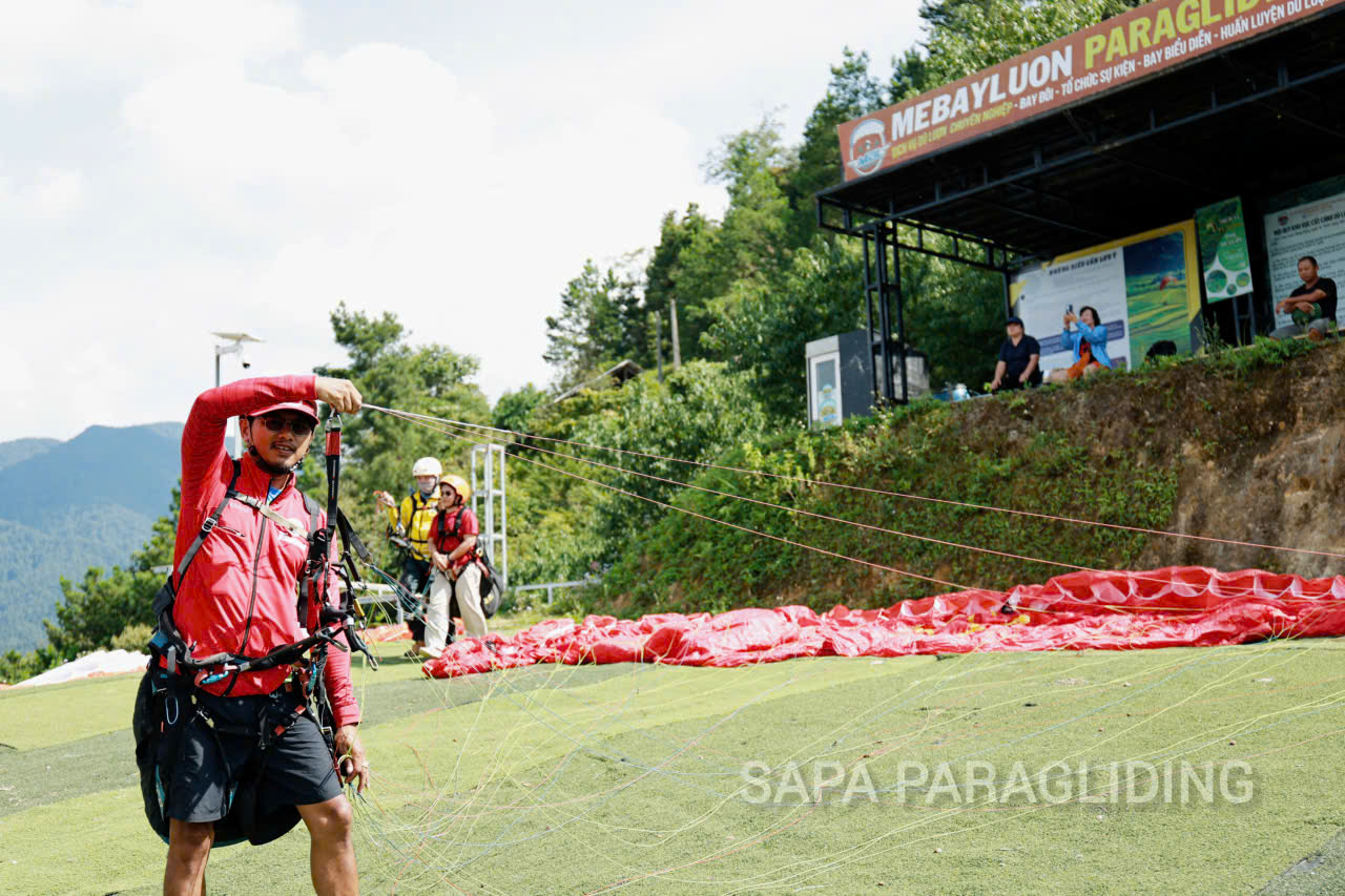 Pilot Dang Van My inspecting a paraglider before flight