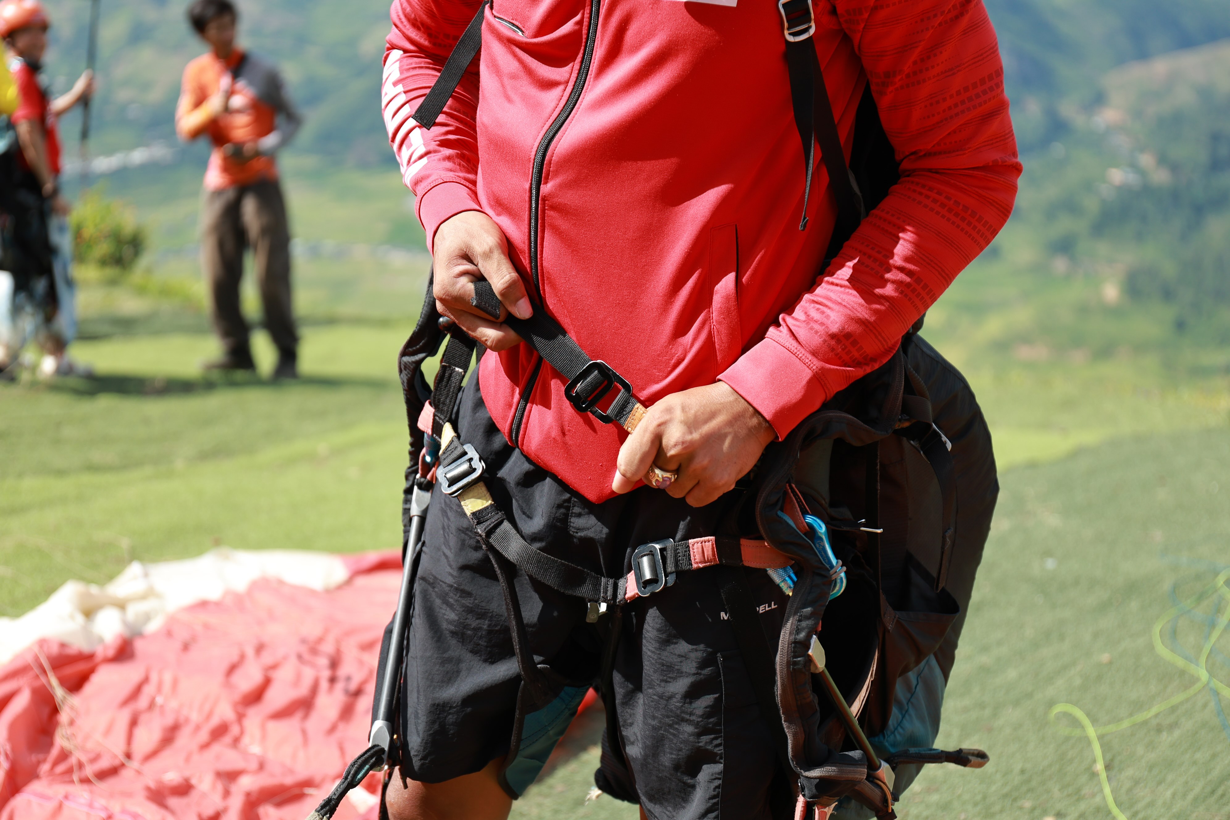 The pilot straps into his own harness and checks every buckle.