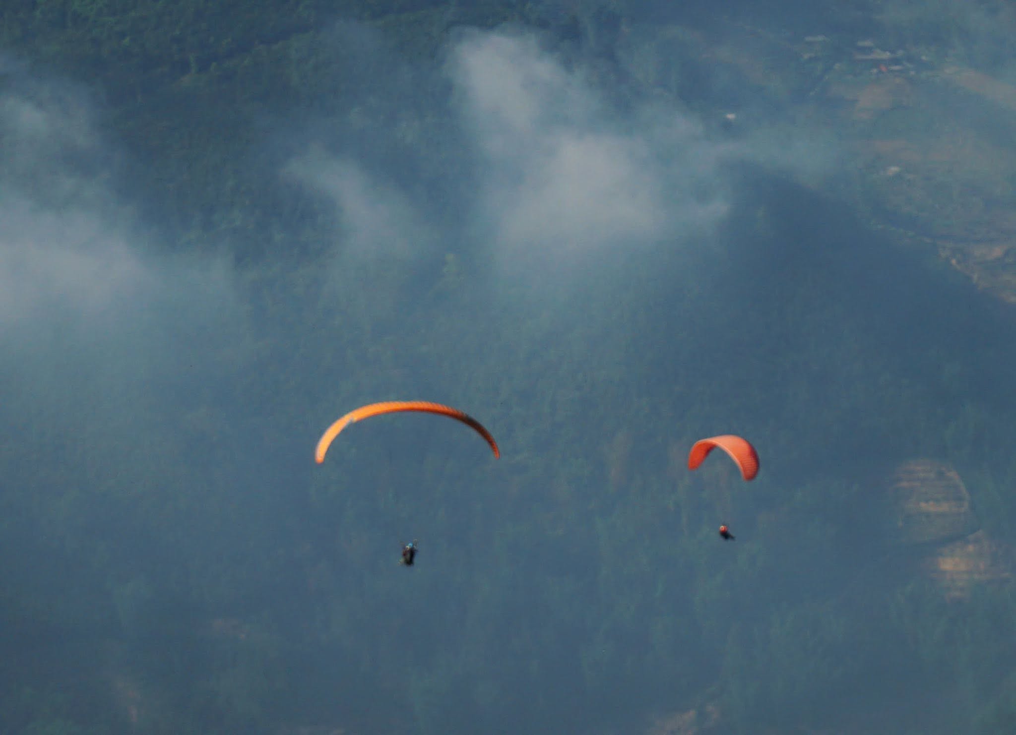 Two paragliders sharing the sky on an overcast day in Sapa