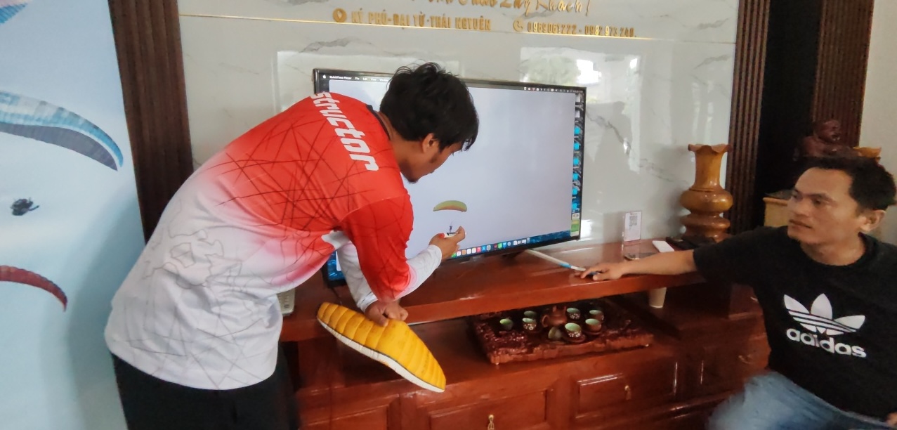 Huấn luyện viên xem lại bài tập qua màn hình và phân tích kỹ thuật.