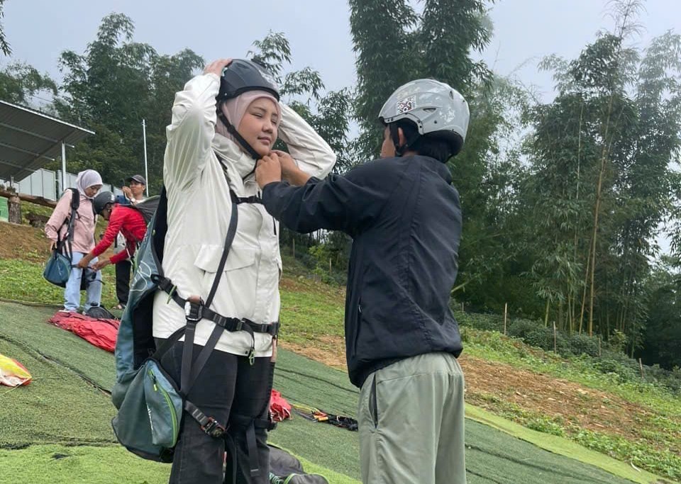 A pilot fitting a passenger's helmet before take-off at the Sapa launch site