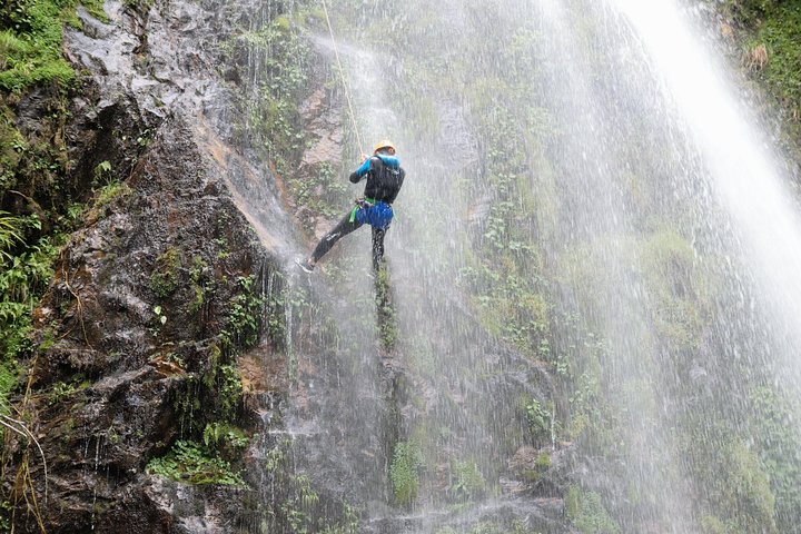 Tourist rappelling down a waterfall and sliding natural water chutes on a Canyoning tour in Sapa