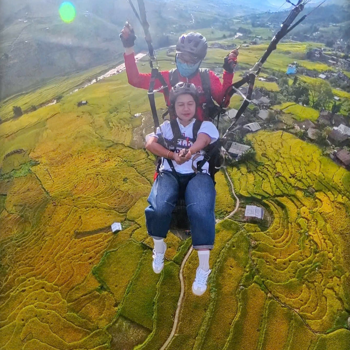Passenger and pilot flying tandem above golden rice terraces in Sa Pa