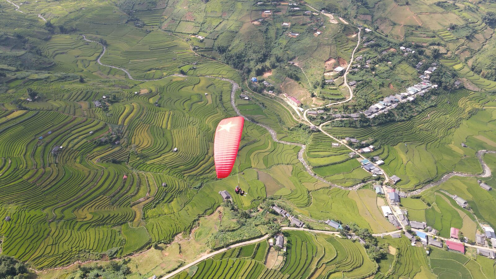 A paraglider over the Mu Cang Chai rice terraces, drone shot