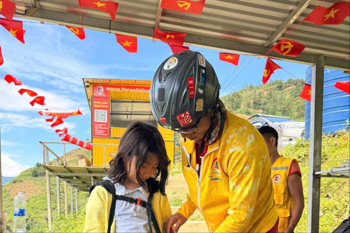 Phi công Sapa Paragliding mặc đai an toàn cho khách trên bãi cất cánh