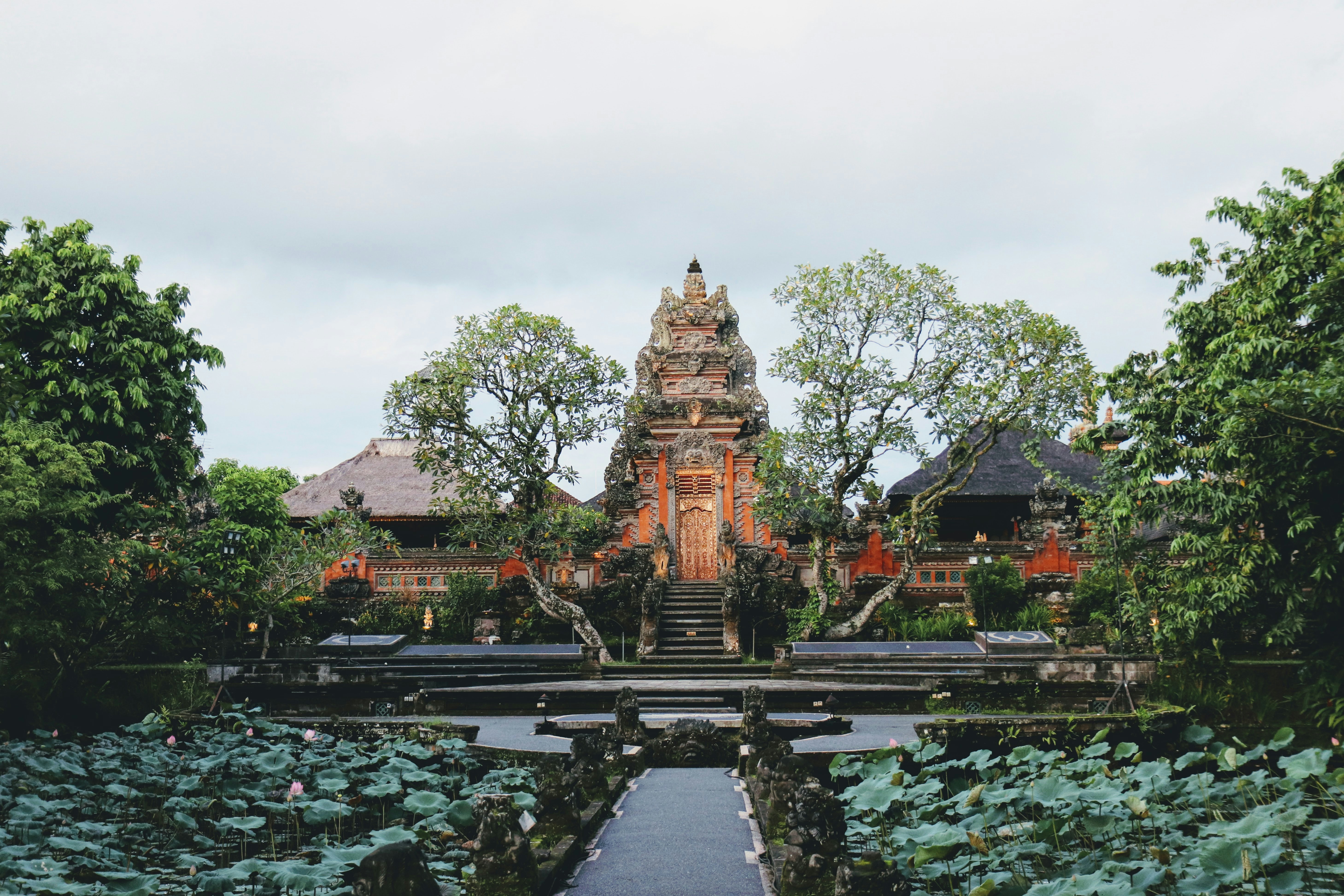 A beautiful temple entrance surrounded by lush greenery and lotus ponds, offering a peaceful and serene atmosphere.
