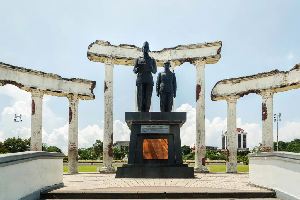 The iconic Tugu Pahlawan in Surabaya, a towering monument dedicated to the heroes of Indonesia's independence, set against the clear blue sky and surrounded by a large open plaza.